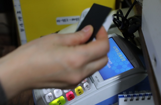 An employee swipes a customer's credit card through the reader at a restaurant in Seoul on Dec. 23, 2021. (Yonhap)