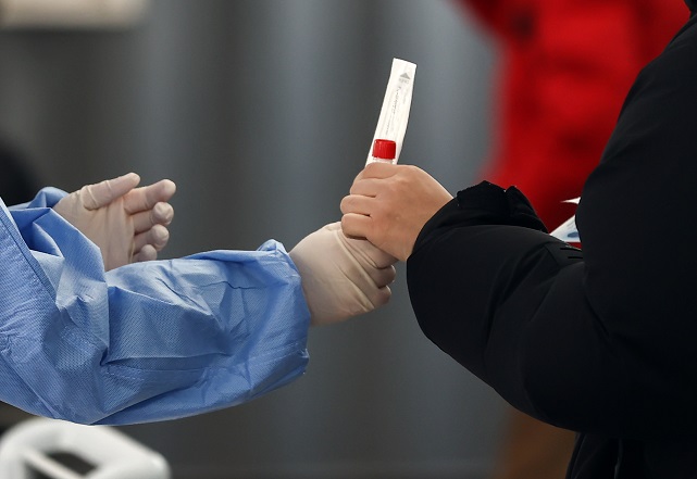 This Dec. 28, 2021, file photo shows a medical worker handing a COVID-19 testing kit to a person at a COVID-19 testing center in central Seoul. (Yonhap)