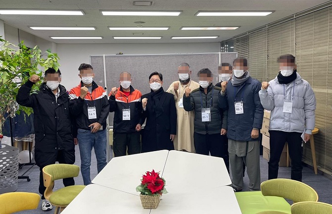 Justice Minister Park Beom-kye (4th from L) and seven Afghan evacuees who recently found jobs in South Korea pose for the camera, in this photo provided by the justice ministry on Jan. 3, 2022. 