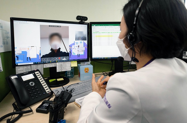 A medical worker talks to a coronavirus-infected patient via video link at a medical facility in Seongnam, near Seoul, on Jan. 21, 2022. (Pool photo) (Yonhap)