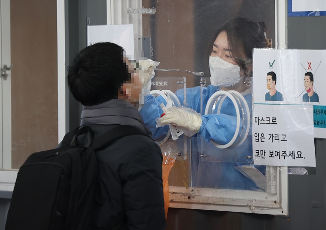 A medical worker carries out a COVID-19 test on a man at a makeshift testing station at Seoul Station in Seoul on Jan. 28, 2022. (Yonhap)