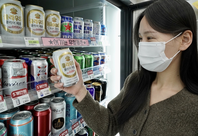 This photo provided by convenience store chain 7-Eleven shows a customer looks at a can of  non-alcoholic beer at a 7-Eleven outlet.