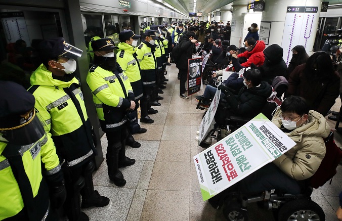 Members of an organization for the physically challenged confront policemen while holding a news conference at a subway station in Seoul on Jan. 3, 2022, calling for better accessibility on the subway. (Yonhap)
