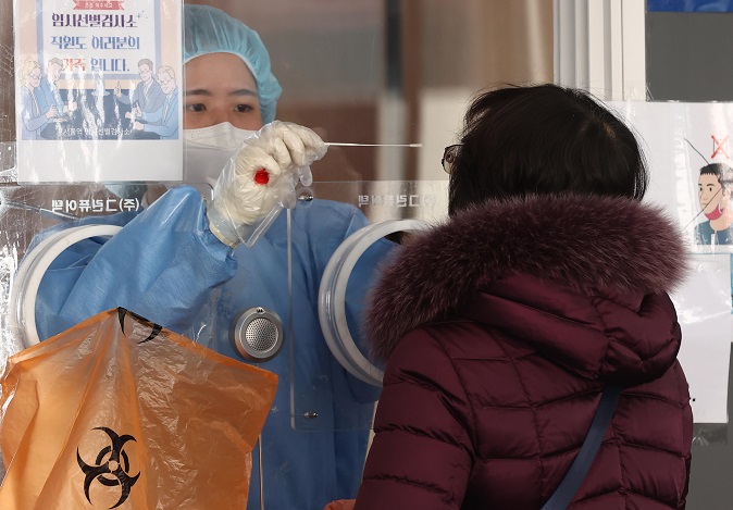 A medical worker collects a swab sample for a coronavirus test at a makeshift COVID-19 testing facility in Seoul on Feb. 27, 2022. (Yonhap)