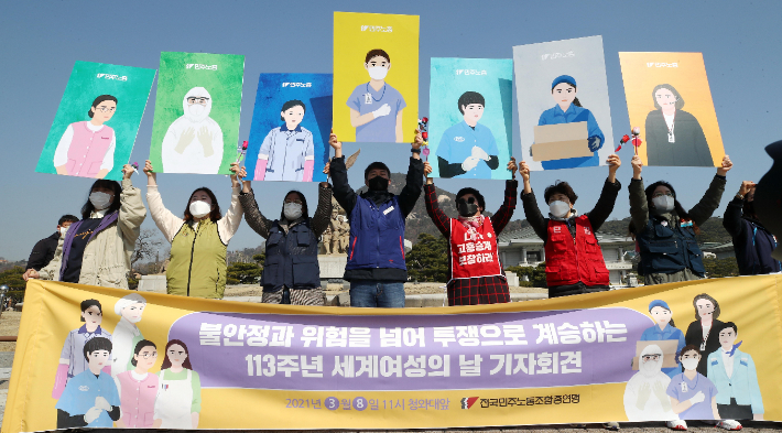 Members from the Korean Confederation of Trade Unions hold up paintings of female laborers during a news conference to mark International Women's Day near the presidential office in Seoul on March 8, 2021. (Yonhap)