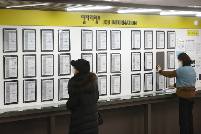 People look at employment information put up on a bulletin board at a state-run job center in Seoul, in this file photo from Feb. 16, 2022. (Yonhap)