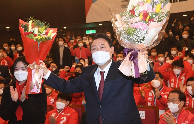 President-elect Yoon Suk-yeol poses for photos after receiving flowers in his party's election situation room at the National Assembly in Seoul on March 10, 2022. (Pool photo) (Yonhap)
