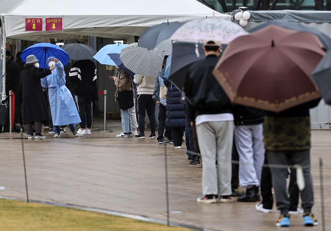 This photo, taken March 13, 2022, shows people waiting in line to receive COVID-19 tests at a temporary testing center in Seoul Plaza in central Seoul. (Yonhap)