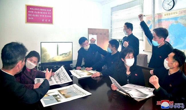 North Korean people cheerfully watch the news on the country's recent ICBM test, in this photo released by the Korean Central News Agency on March 26, 2022. (Yonhap)