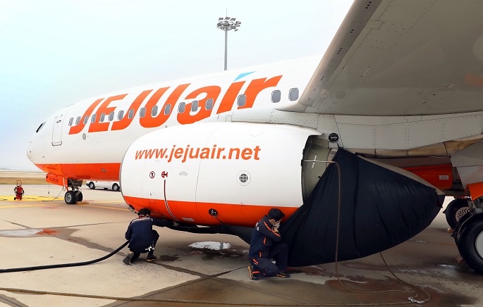 This photo provided by Jeju Air Co. shows workers using a pressurized wand to clean off engine fan blades.