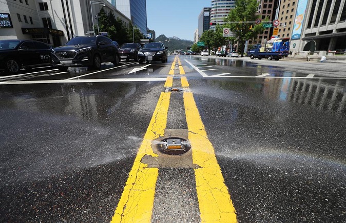 Water sprays from a cooling road system set up on the centerline of Sejong Street in downtown Seoul to cool down the hot road amid a heat wave on June 15, 2020. (Yonhap)