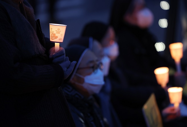 Participants hold candles at a rally urging Russia to stop its invasion of Ukraine in front of the Russian Embassy in Seoul on March 18, 2022. (Yonhap)