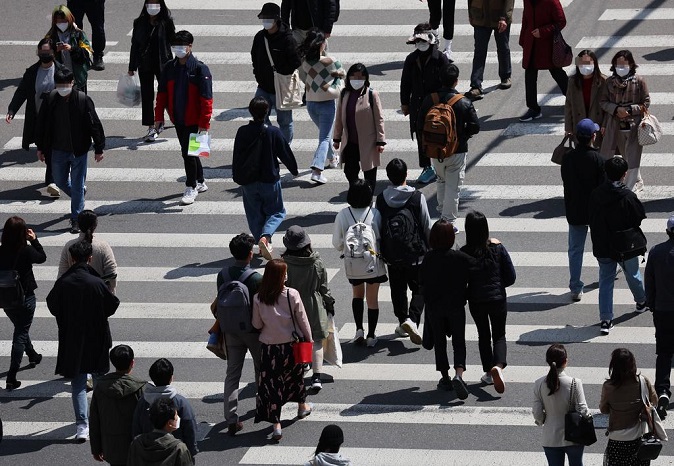 People wearing face masks walk in front of Yongsan Station in Seoul on April 1, 2022. (Yonhap)