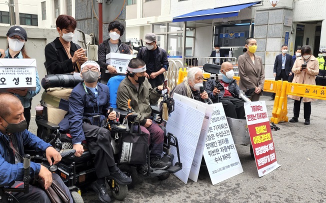 Park Kyoung-seok (front, 4th from L), the chief of Solidarity Against Disability Discrimination, speaks in a news conference held in front of Hyehwa Police Station in central Seoul on April 25, 2022, before attending police questioning for organizing daily rush-hour subway riding protests. (Yonhap)
