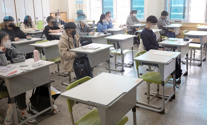 This undated file photo shows students wearing masks as they sit for an exam. (Yonhap)