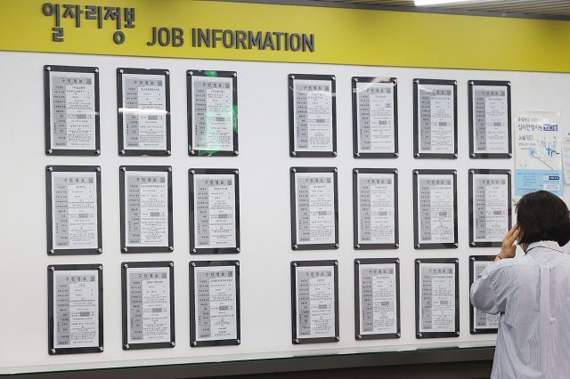 In this April 19, 2022, file photo, a job seeker looks at job information posted on a bulletin board at an employment center in western Seoul. (Yonhap)