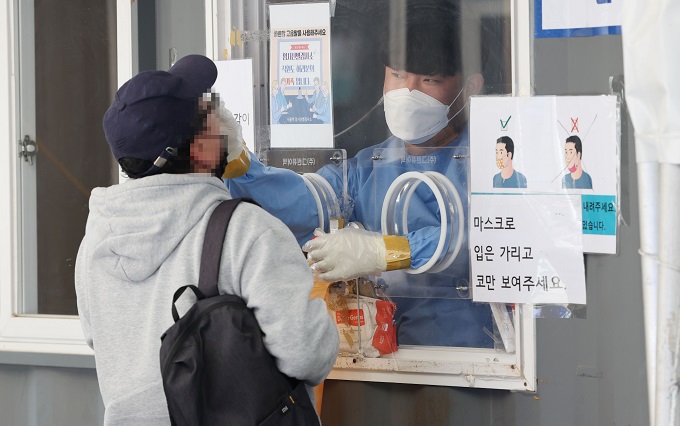 A health worker conducts a COVID-19 test on a citizen at a testing site in front of Seoul Station on May 5, 2022. (Yonhap)