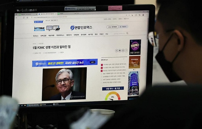 A currency trader reads a news report on the U.S. Federal Reserve's decision to raise key interest rates by half a percentage point at the dealing room of Hana Bank in Seoul on May 6, 2022. (Yonhap)