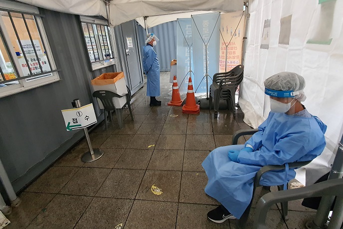 Medical workers stand by at a quiet COVID-19 testing booth in Seoul's central district of Jongno, in this photo taken May 18, 2022, amid a decline in the infection numbers. (Yonhap)
