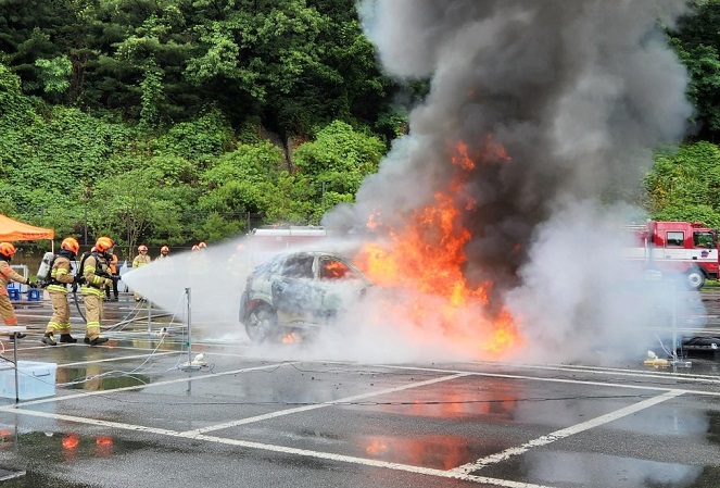 This photo provided by the Seoul Metropolitan Fire and Disaster Headquarters shows firefighters put out a fire on an electric car during a drill at the Seoul Metropolitan Fire Academy in the South Korean capital.