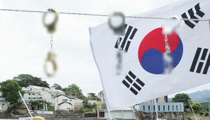 Replica handcuffs are hung during a rally in front of former President Moon Jae-in's residence in Yangsan, southeastern South Korea, in this file photo taken June 8, 2022. (Yonhap)