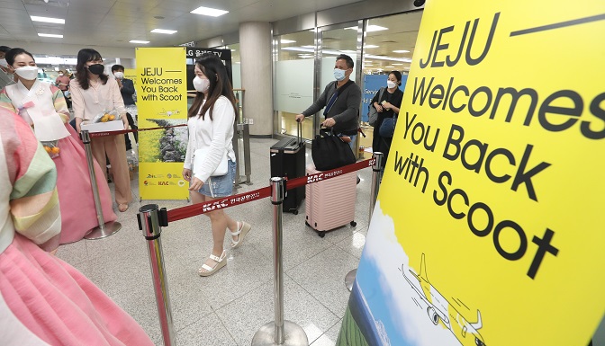 Jeju Island officials welcome international tourists at Jeju International Airport on June 15, 2022. They arrived on the island on Singaporean budget carrier Scoot's aircraft as the company launched a direct flight between Singapore and Jeju. (Yonhap)