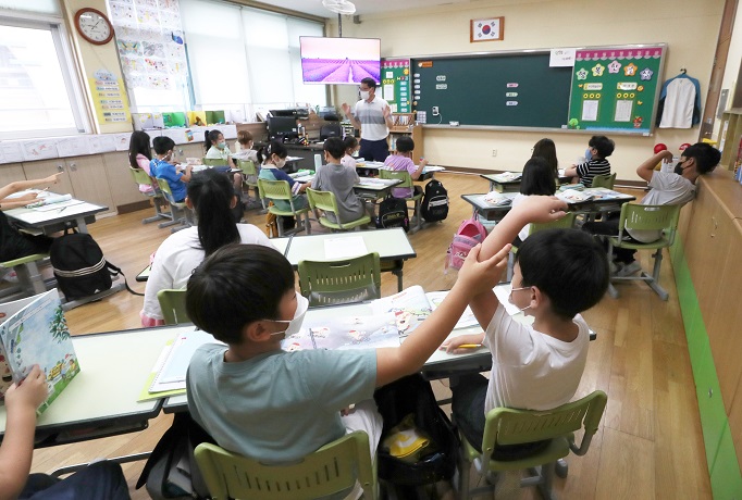 Students sit at desks that no longer have plastic dividers meant to stop spread of the coronavirus at an elementary school in Chuncheon, Gangwon Province, on June 28, 2022. (Yonhap)