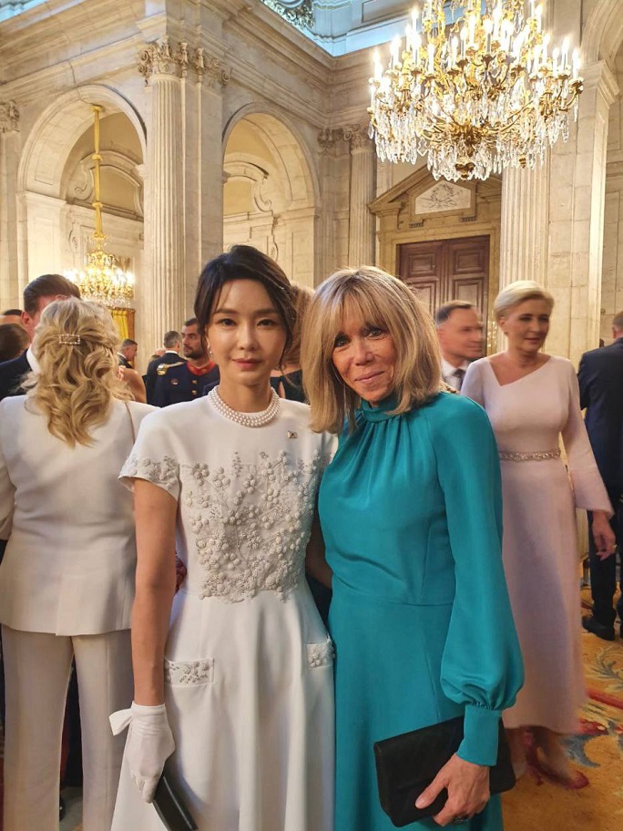 This photo, provided by the presidential office, shows first lady Kim Keon-hee (L) and French first lady Brigitte Macron posing for a photo at a gala dinner held at the Royal Palace of Madrid on June 28, 2022.