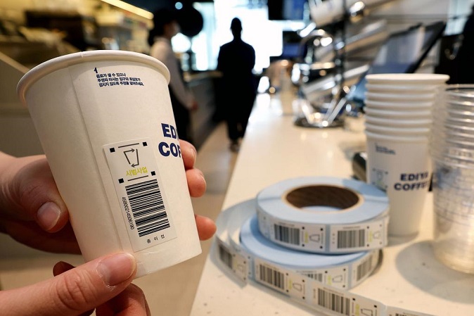 This file photo shows a barcode sticker pasted on a disposable cup during an environment ministry-hosted demonstration of a deposit-return scheme at a cafe in central Seoul in May. (Yonhap)