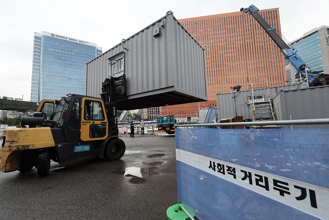 Workers remove a container building used as a makeshift clinic for coronavirus tests in front of Seoul Station on July 1, 2022, as South Korea has seen COVID-19 cases declining. (Yonhap)