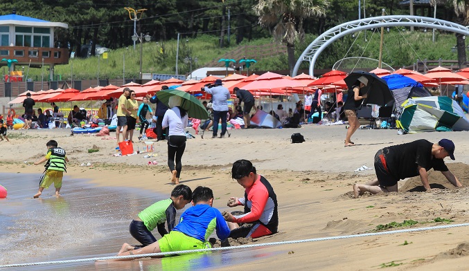 Visitors spend time at a beach on Jeju Island, off the southern coast, on July 3, 2022. (Yonhap)