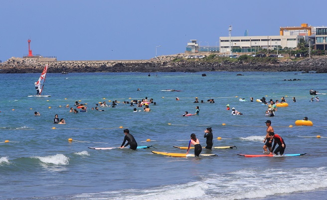 Vacationers spend time at Samyang Beach on the southern resort island of Jeju on July 9, 2022. (Yonhap)