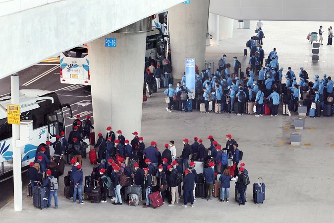 Migrant workers wait in line at bus stops upon arriving at Incheon International Airport, west of Seoul, on July 7, 2022, as they entered the country under the work permit system amid eased quarantine rules. (Yonhap)