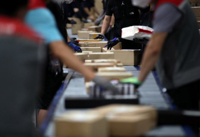 Delivery workers sort items that have to be delivered at a logistics center in Seoul in this file photo. (Yonhap)