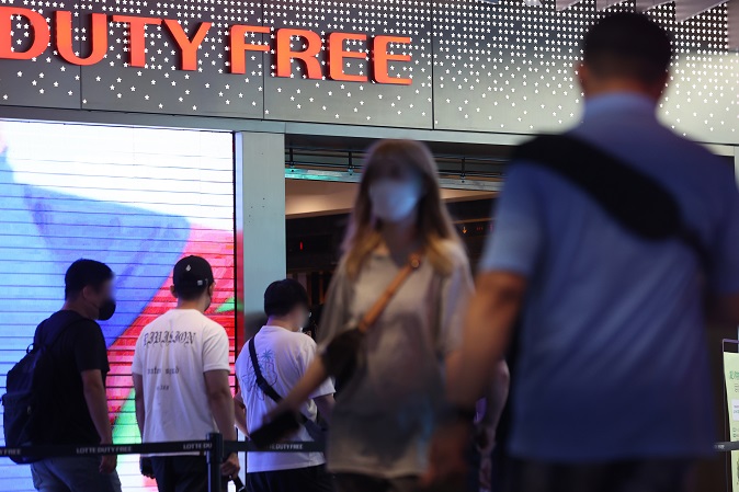 This file photo, taken July 18, 2022, shows South Koreans and foreigners awaiting to enter a duty-free store in Seoul. (Yonhap)