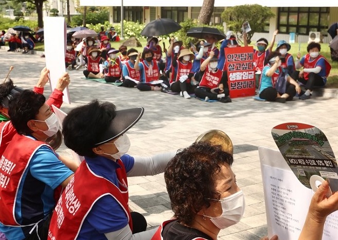 A group of workers in cleaning and security jobs chants slogans during a rally at Seoul's Yonsei University on July 19, 2022, to call for a wage increase and better working conditions. (Yonhap)
