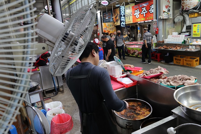 A cook prepares food for customers at a traditional market in the southwestern city of Gwangju on Aug. 1, 2022. (Yonhap)