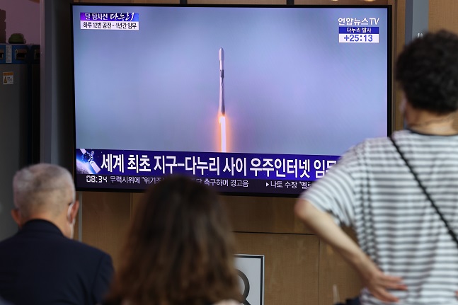 People watch a TV report at Seoul Station on Aug. 5, 2022, about a SpaceX Falcon 9 rocket carrying South Korea's first lunar orbiter, the Korea Pathfinder Lunar Orbiter known as Danuri, lifting off from Cape Canaveral Space Force Station in Florida, the United States. (Yonhap)