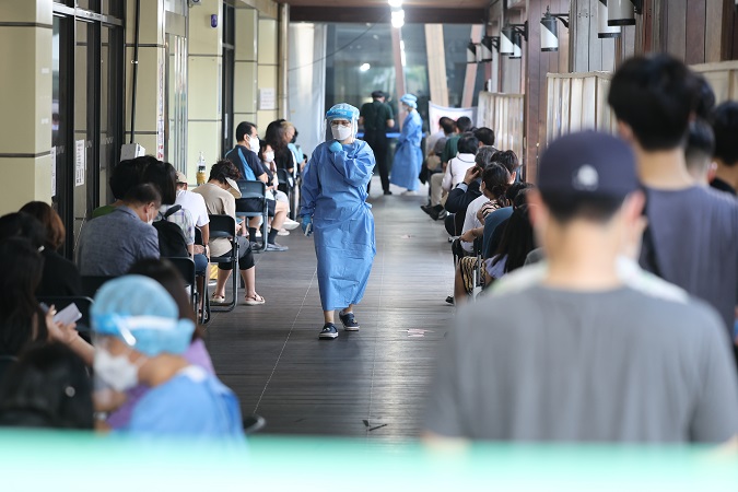 People wait in line for tests at a COVID-19 testing center in Seoul on Aug. 12, 2022. (Yonhap)