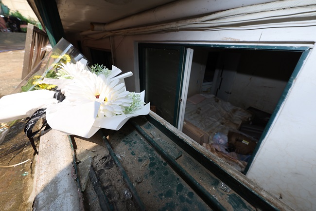 Flowers are placed at a ground level window of a semi-basement apartment in Seoul's Gwanak Ward on Aug. 12, 2022, where three family members were stranded and later found dead after heavy rainfall began pounding the capital city and parts of central South Korea on Aug. 8. (Yonhap)