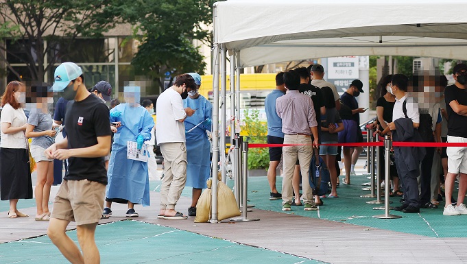 People line up to undergo COVID-19 tests at a makeshift testing station in Seoul on Aug. 16, 2022. (Yonhap)