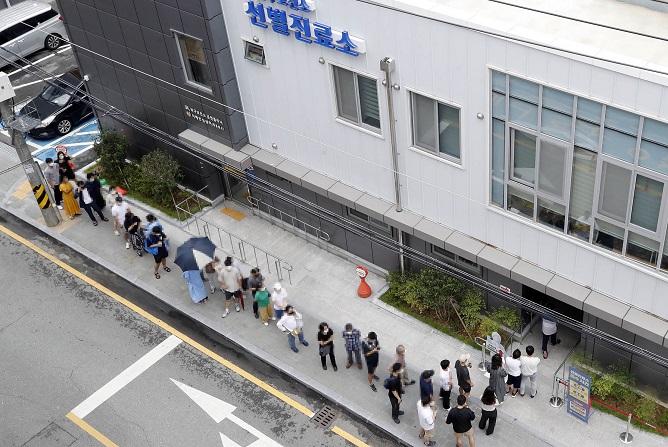 This photo, provided by a ward office in the southwestern city of Gwangju, shows people waiting to undergo COVID-19 tests in the city on Aug. 16, 2022.