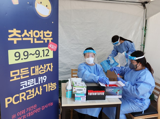 Medical workers put COVID-19 test kits on a table at a testing booth set up in a rest area near a highway in Yongin, 40 kilometers south of Seoul, on Sept. 7, 2022. (Yonhap)