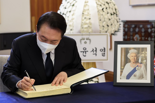 This photo, provided by the presidential office, shows President Yoon Suk-yeol signing a condolence book for late British Queen Elizabeth II in front of a memorial altar for her set up at the British Council in Seoul on Sept. 9, 2022. 