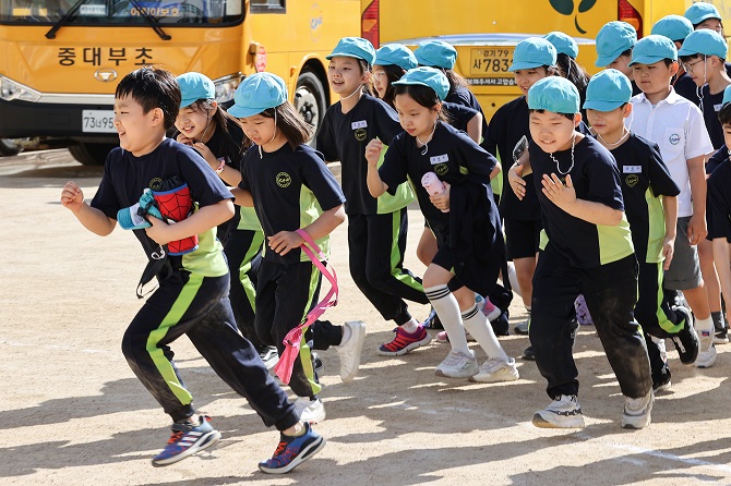 Students without masks take part in a physical education class at an elementary school in Seoul on Sept. 26, 2022. South Korea lifted all outdoor mask mandates starting the same day, as the country is "clearly overcoming" a resurgence in COVID-19 cases. But the indoor mask mandate will continue to be kept. (Yonhap)