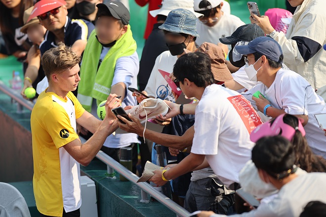 Jenson Brooksby of the United States (L) signs autographs for fans after defeating Kwon Soon-woo of South Korea in the second round of the men's singles at the ATP Eugene Korea Open at Olympic Park Tennis Center in Seoul on Sept. 29, 2022. (Yonhap)