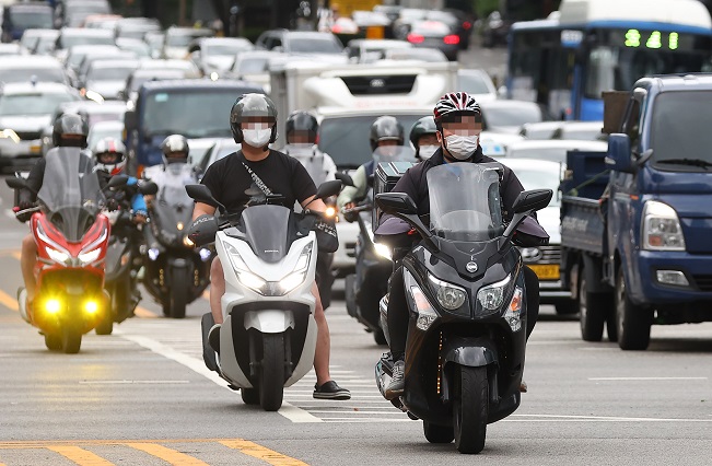 Delivery workers ride motorbikes on a street in Seoul, in this file photo taken June 28, 2022. (Yonhap)