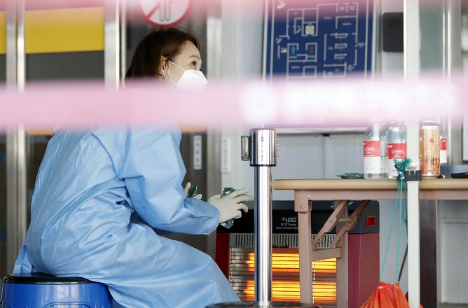 A health worker sits in front of a heater at a coronavirus testing center in the southwestern city of Gwangju on Oct. 18, 2022, in this photo provided by the city's Buk ward office.