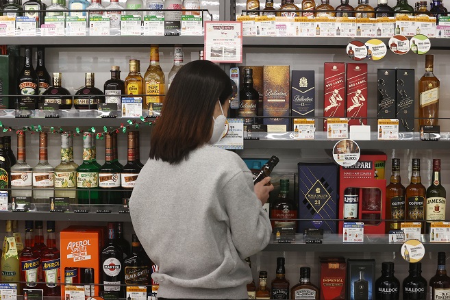 A customer looks at bottles of whiskey at a convenience store in Seoul in this file photo taken on March 10, 2022. (Yonhap)