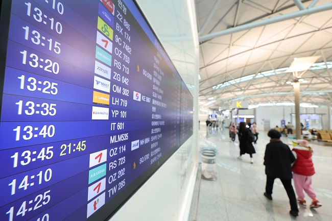 This undated file photo shows travelers walking past an arrival departure board at Incheon International Airport, west of Seoul. (Yonhap)
